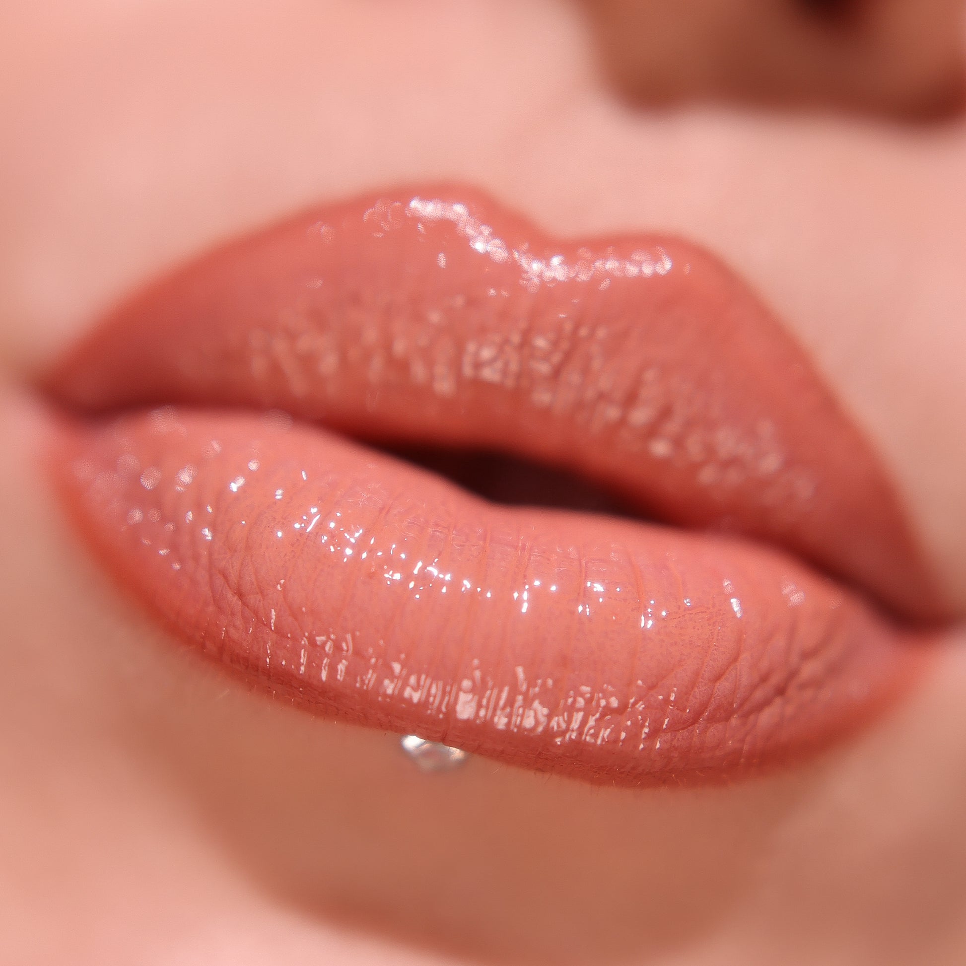 Close-up of Miss Bombshell, peachy glossy lips with a neutral background
