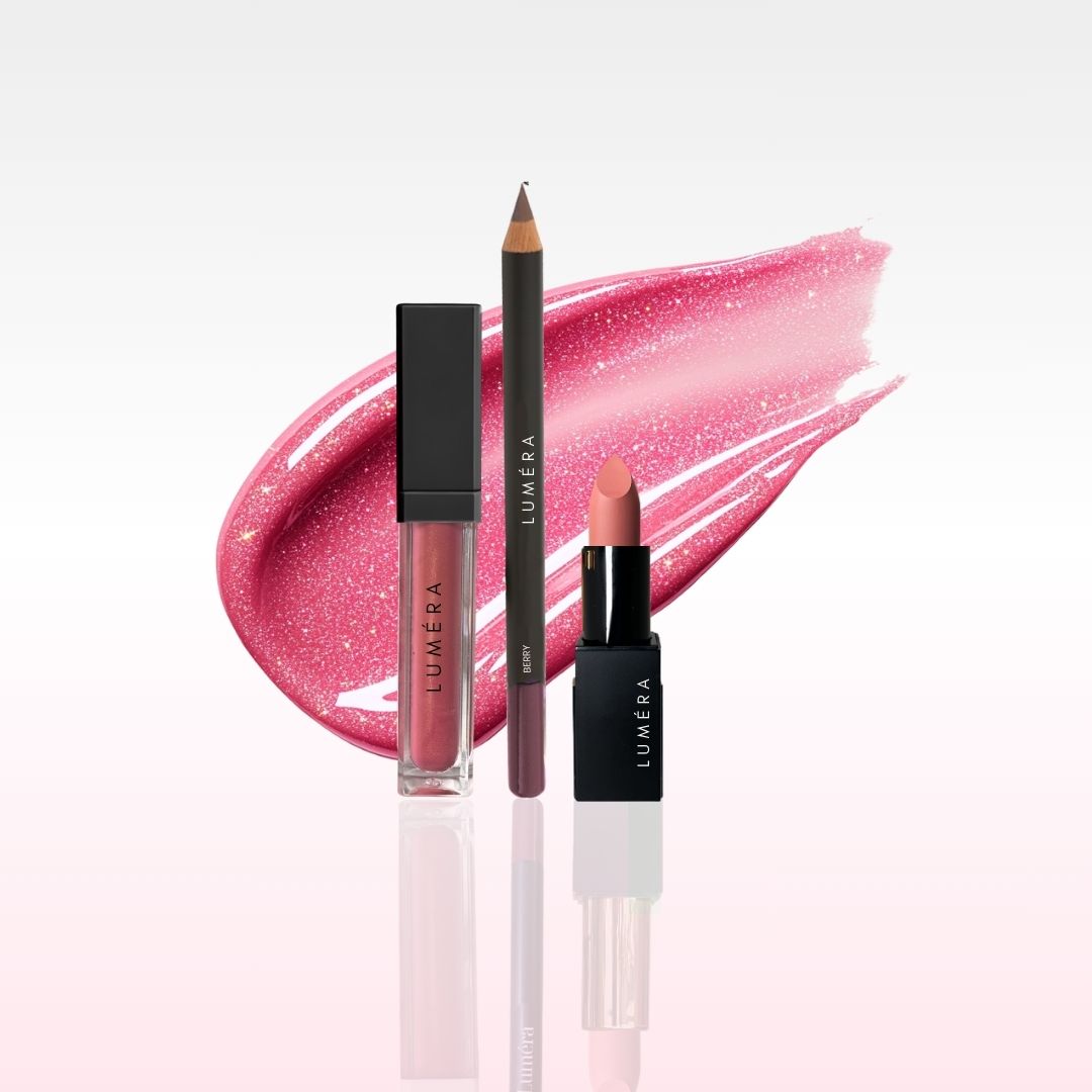 Lumiera lip products including a lip gloss, lip liner, and lipstick on a light pink background.