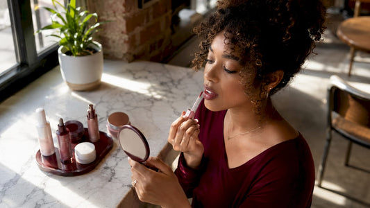 Woman applying hydrating lip gloss in bathroom