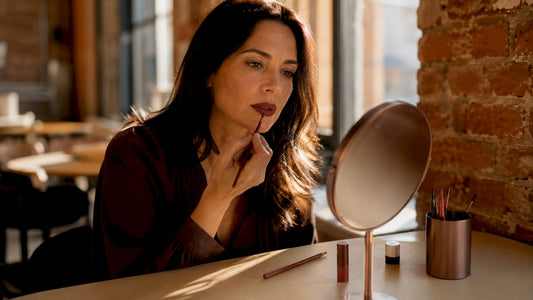 Mature woman carefully applying lipstick at vanity