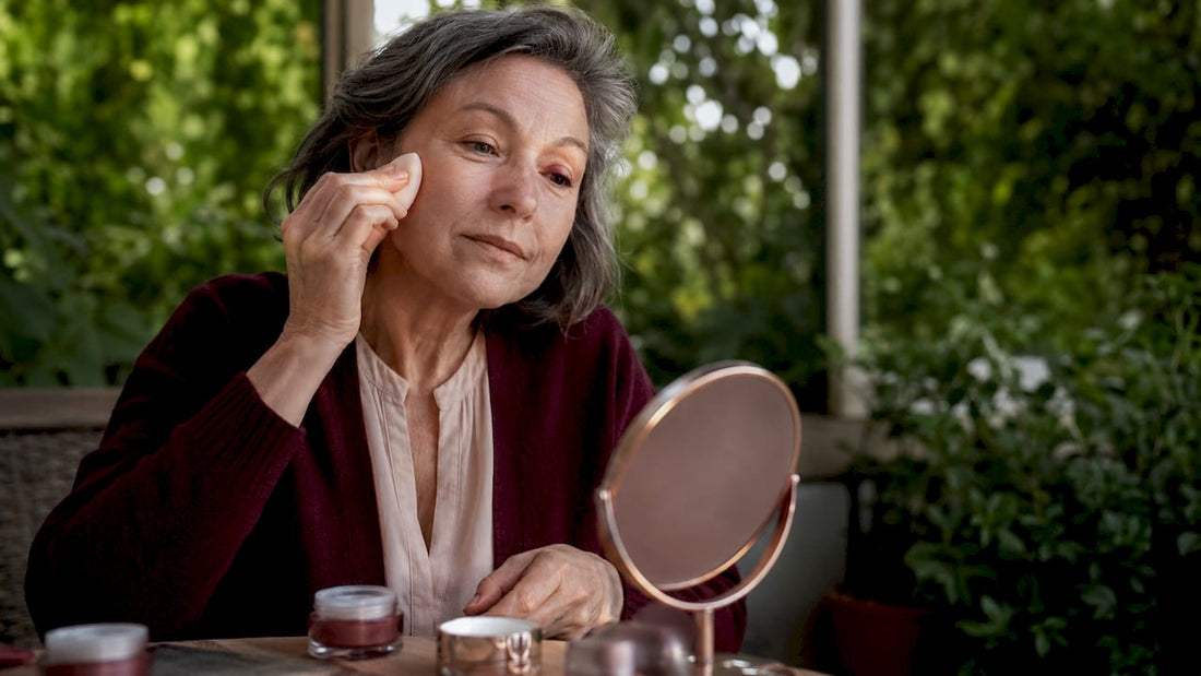 Mature woman applying hydrating foundation at vanity