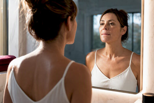 Mature woman assessing hydrated lips in mirror