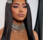 Woman with long straight hair wearing silver jewelry against a neutral background